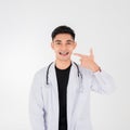 Portrait of Asian young man doctor in white gown standing with showing and pointing to dental braces in mouth isolated on white