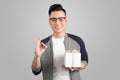 Portrait of asian young man holding gift box over gray Royalty Free Stock Photo