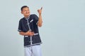 Portrait of Asian young man wearing karate uniform laughing at funny crazy joke with hands over body isolated over gray background Royalty Free Stock Photo