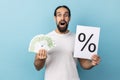 Man holding paper with percent sign inscription and euro banknotes, looking at camera. Royalty Free Stock Photo