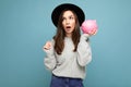 Portrait of astonished amazed young nice attractive woman with dark hair wearing stylish gray sweater and black hat Royalty Free Stock Photo