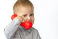 Portrait of an astonished cute little boy holding a red telephone receiver.
