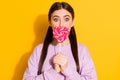 Portrait of astonished funny girl close cover her lips with tasty heart shape candy lolipop wear pullover isolated over