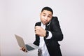 Portrait astonished handsome young man in white shirt, black jacket holding laptop, speaking on phone on white