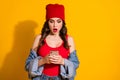Portrait of astonished millennial teen girl use smart phone read social network post feedback impressed scream wear red