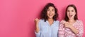 Portrait of astonished women pointing fingers aside at copy space isolated over pink background, surprising females with surprised Royalty Free Stock Photo