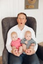 Funny surprised dad with two babies on his knees. Royalty Free Stock Photo