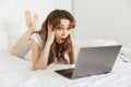 Portrait of an astonished young woman lying in bed at home