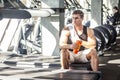 Portrait of athlete handsome masculine man sitting during treadmill exercise in gym, tired sportsman drinking water in sports hall Royalty Free Stock Photo