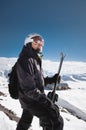 Portrait athlete skier in helmet and ski mask against the snow-capped mountains of a ski resort with a reflection of the