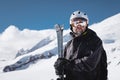 Portrait athlete skier in helmet and ski mask against the snow-capped mountains of a ski resort with a reflection of the