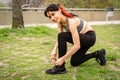 Portrait of an athletic woman tying her shoelaces and getting ready for jogging in public park . Sport and healthy lifestyle Royalty Free Stock Photo