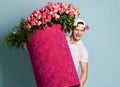 Portrait of athletic young winking man delivery guy holding huge valentines day pink box with flowers roses Royalty Free Stock Photo