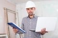 Portrait of attentive architect working at the notebook in helmet with documents