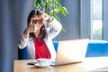 Portrait of attentive beautiful stylish brunette young woman in glasses sitting and looking at camera with crop composition hand