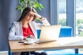 Portrait of attentive beautiful stylish brunette young woman in glasses sitting and reading something important on her laptop Royalty Free Stock Photo