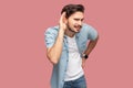 Portrait of attentive handsome bearded young man in blue casual style shirt standing with hand on ear and trying to hear something