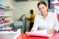 Portrait of an attentive woman checking quality of printing in printing house Royalty Free Stock Photo