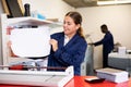 Portrait of an attentive woman checking quality of printing in printing house Royalty Free Stock Photo