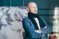 Portrait of attractive adult successful bald man art critic historian with beard in scarf in art gallery