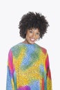 Portrait of an attractive African American woman in multicolored dashiki standing over gray background