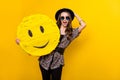Portrait of attractive amazed cheerful girl holding in hands emoticon wow reaction isolated over bright yellow color