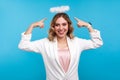 Portrait of attractive angelic woman pointing at halo on her head and smiling. isolated on blue background Royalty Free Stock Photo