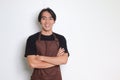 Portrait of attractive Asian barista man in brown apron keeping arms crossed and looking at camera. Advertising concept. Isolated Royalty Free Stock Photo