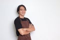 Portrait of attractive Asian barista man in brown apron keeping arms crossed and looking at camera. Advertising concept. Isolated Royalty Free Stock Photo