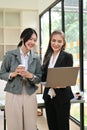Attractive Asian businesswoman enjoys talking with her colleague while taking a coffee break Royalty Free Stock Photo