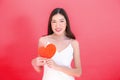 Portrait of attractive Asian smiling woman holding red heart paper jigsaw isolated on pink red background. Royalty Free Stock Photo