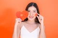 Portrait of attractive Asian smiling woman holding red heart paper jigsaw on pink red background. Royalty Free Stock Photo