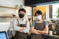 Portrait of attractive Asian waiter and waitress at restaurant cafe. Barista business couple in apron wearing protective mask , Royalty Free Stock Photo