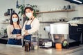 Portrait of attractive Asian waiter and waitress at restaurant cafe. Barista business couple in apron wearing protective mask , Royalty Free Stock Photo