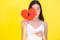 Portrait of attractive Asian woman holding red heart paper jigsaw on pink red background. Royalty Free Stock Photo