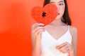 Portrait of attractive Asian woman holding red heart paper jigsaw on pink red background. Royalty Free Stock Photo