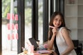 Portrait of attractive asian woman looking at camera smiling with confident working with smart tablet and positive Royalty Free Stock Photo