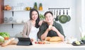 Portrait of attractive Asian young couple using tablet at kitchen, smiling, looking at camera, enjoy cooking preparing healthy Royalty Free Stock Photo