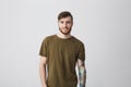 Portrait of attractive bearded caucasian man with tattoo on arm and stylish hairstyle wearing casual green t-shirt