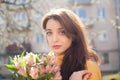 Portrait of attractive and beautiful young woman in yellow jacket holding a big bouquet of colorful flowers outdoors Royalty Free Stock Photo