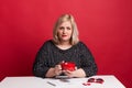 Portrait of an attractive overweight woman in studio on a red background.