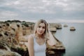 Portrait of attractive blonde woman posing wears straw hat on rocky beach on sunset background Royalty Free Stock Photo