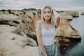 Portrait of attractive blonde woman posing wears straw hat on rocky beach on sunset background Royalty Free Stock Photo