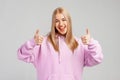 Portrait of attractive blonde girl, showing thumbs up and smiling satisfied, recommending store or brand, give approval, like and Royalty Free Stock Photo