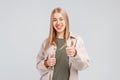 Portrait of attractive blonde girl, showing thumbs up and smiling satisfied, recommending store or brand, give approval, like and Royalty Free Stock Photo