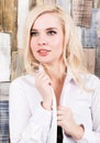 Portrait of attractive blonde girl standing on wood wall background. She has blue eyes and dressed in a man`s shirt Royalty Free Stock Photo
