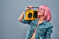 Portrait of an attractive bright young girl dressed in denim jacket holding record player on her shoulder while standing and Royalty Free Stock Photo