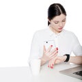 Portrait of attractive brunette businesswoman in white shirt sitting, holding smartphone mobile and looking at display of her Royalty Free Stock Photo