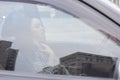 portrait of attractive brunette in grey checkered dress in a black car. girl in automobile. business woman