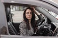 portrait of attractive brunette in grey checkered dress in a black car. girl in automobile. business woman